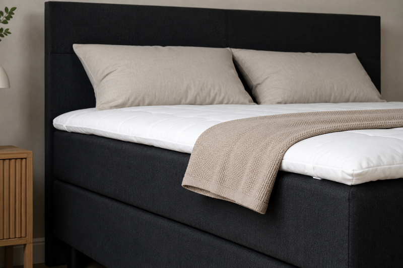 Zwarte boxspring BestRest met wit beddengoed en plaid, van dichtbij